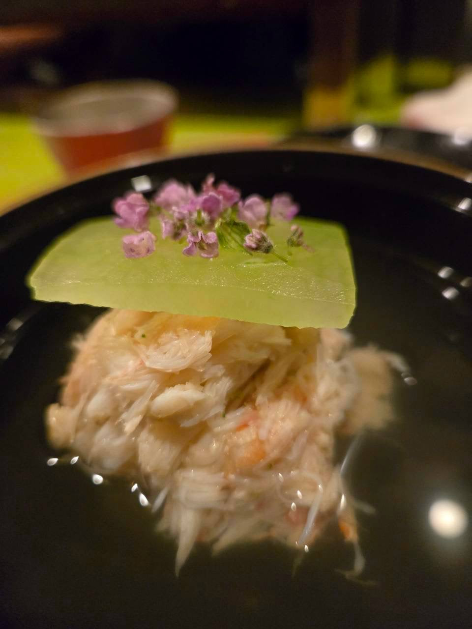 食堂とだかの蟹と冬瓜のお椀。薄切りの冬瓜の上に紫の穂じその花が添えられている
